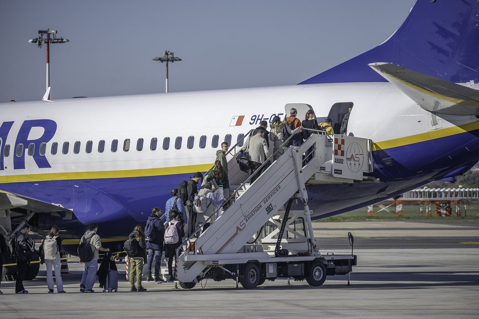 Passagers avec bagages cabine montant l'escalier d'embarquement d'un Boeing 737 low-cost