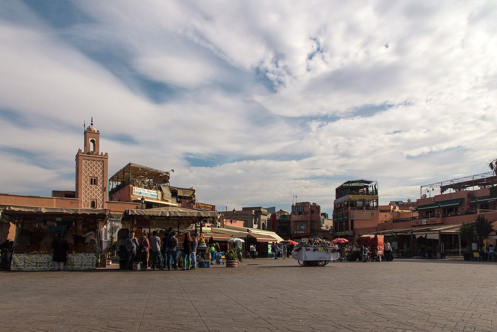 La place Jemaa el-Fna en journée, minaret et étals de jus d'orange